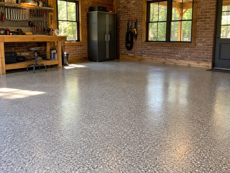 Speckled flake floor in a brick-walled workshop with a wooden workbench and sunny windows